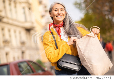 Woman with a papaer bag after shopping in a city street 96724361