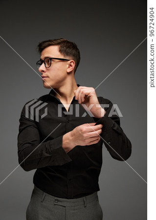Successful young man in business classic style outfit adjusting his shirt sleeve isolated over grey background. Fashion look of businessman. Office style 96724904