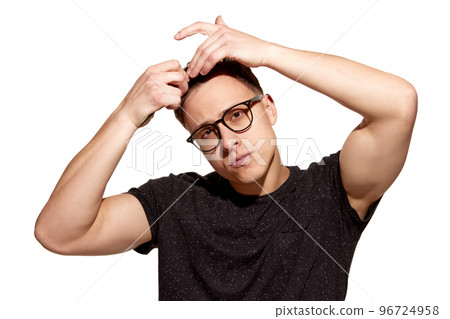 Young handsome man in casual T-shirt combs his hair with hands. Well-being. Concept of men's health, body and hair care 96724958