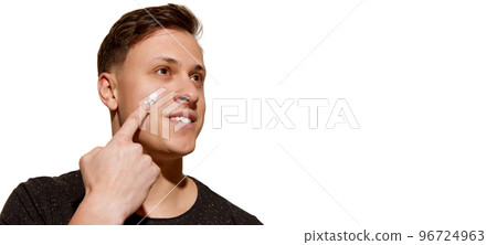 Facial skin care for man. Young attractive man with perfect well-kept skin using face cream isolated over white background. Cosmetics, health care, skin care, beauty Facial skin care for man. Young attractive man with perfect well-kept skin using face cream isolated over white background. Cosmetics, health care, skin care, beauty 96724963
