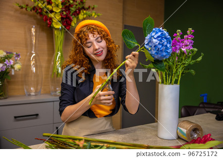 Florist preparing flowers for bouquets and looking involved 96725172