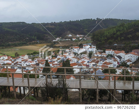 Aerial view over the town Odeceixe, white houses traditional village surrounded by Rio Seixe river, green hills and fields with grazing cows. Alentejo, Portugal. 96726202