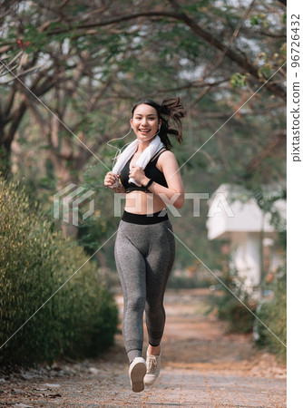 Sporty asian young woman running on park road in beautiful nature Sporty asian young woman running on park road in beautiful nature 96726432