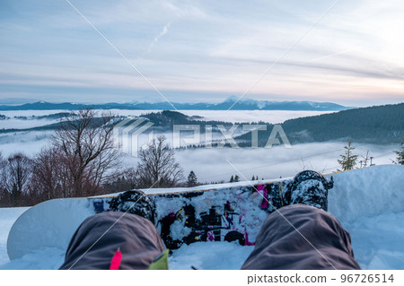 snowboarder enjoying the view of sunset above the mountains snowboarder enjoying the view of sunset above the mountains 96726514