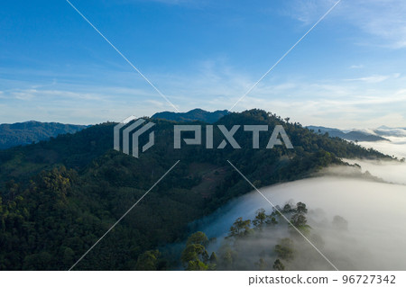 aerial view scenery sunrise above the mountain in tropical rainforest. slow floating fog blowing cover on the mountain look like as a sea of mist. beautiful sunrise in the mist background. aerial view scenery sunrise above the mountain in tropical rainforest. slow floating fog blowing cover on the mountain look like as a sea of mist. beautiful sunrise in the mist background. 96727342