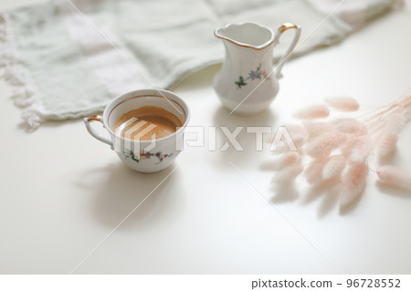 cup with coffee and milk jug on a white wooden background, closeup. Energy breakfast, morning routine concept 96728552
