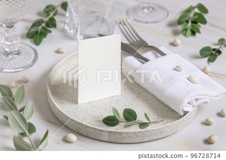 Table setting with folded card decorated with eucalyptus branches close up, Wedding mockup 96728714