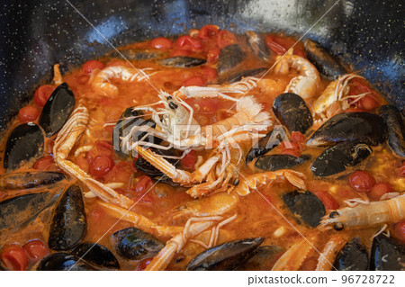 Cooking Italian stew with seafood and tomatoes in a big frying pan, close up Cooking Italian stew with seafood and tomatoes in a big frying pan, close up 96728722