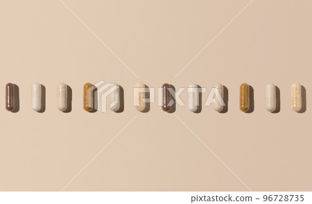 Mix of medical capsules in a line on light beige top view, hard shadows. Dietary supplements Mix of medical capsules in a line on light beige top view, hard shadows. Dietary supplements 96728735