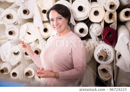 european female buyer chooses fabric on rolls 96729225