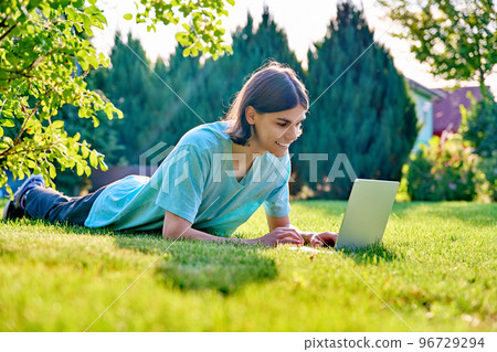 Teenage male lying on the grass using a laptop Teenage male lying on the grass using a laptop 96729294