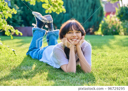Outdoor portrait of young female 18 years old lying on grass 96729295