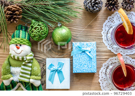 Hot mulled wine with spices on wooden background. Christmas tree branches, gifts and cones. Hot mulled wine with spices on wooden background. Christmas tree branches, gifts and cones. 96729403