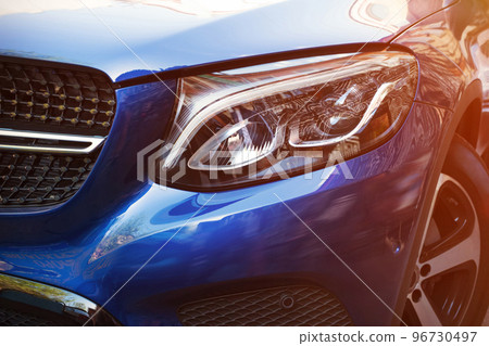 Beautiful headlight of blue car by close-up in a sunny day. Kind with to the side Beautiful headlight of blue car by close-up in a sunny day. Kind with to the side 96730497