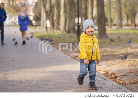 A little boy runs along the path in the park. 96730722