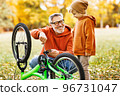 grandfather and grandson repair bicycle outdoors in the autumn park 96731047