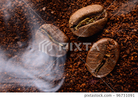 ground coffee and three beans in a light smoke. ground coffee and three beans in a light smoke. 96731091