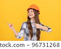 happy teen girl in helmet and checkered shirt pointing finger on copy space, advert 96731268