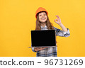 happy teen girl in helmet and checkered shirt presenting laptop, ok 96731269