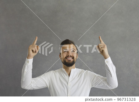 Happy young man smiling and pointing up with both index fingers at copy space above 96731328