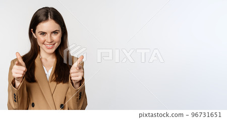 Enthusiastic businesswoman, corporate woman showing thumbs up and smiling, complimenting, recommending company, standing over white background 96731651