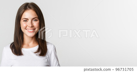 Close-up of attractive brunette girl smiling happy, standing white background 96731705