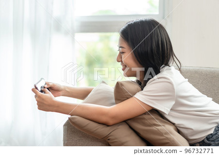 Half-Japanese woman sitting on the sofa using mobile while on vacation, Rest at home, Living room, Relax time, Touch screen tablet, Go on internet, Favorite corner, Personal space Half-Japanese woman sitting on the sofa using mobile while on vacation, Rest at home, Living room, Relax time, Touch screen tablet, Go on internet, Favorite corner, Personal space 96732771