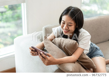 Half-Japanese woman sitting on the sofa using mobile while on vacation, Rest at home, Living room, Relax time, Touch screen tablet, Go on internet, Favorite corner, Personal space 96732773