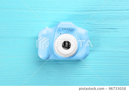 Toy camera on light blue wooden background, top view Toy camera on light blue wooden background, top view 96733038
