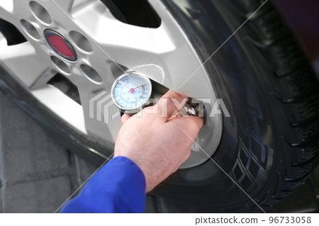 Mechanic checking tire air pressure at car service, closeup 96733058