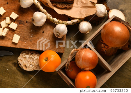 still life of food in a rural style on a dark wood background, sliced cheese, garlic, onion and tomatoes, concept of healthy food 96733230