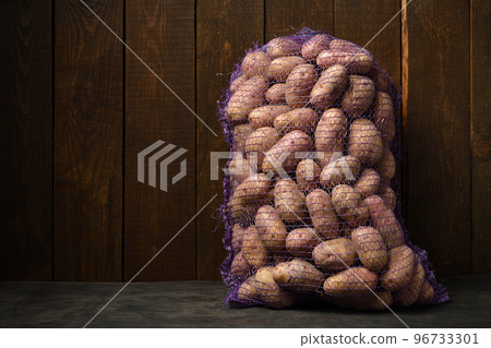 a bag of potatoes on a dark wooden background 96733301