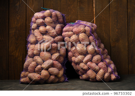 two bags of potatoes on a dark wooden background two bags of potatoes on a dark wooden background 96733302