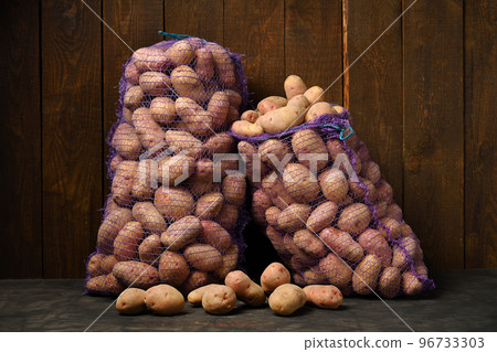 two bags of potatoes on a dark wooden background two bags of potatoes on a dark wooden background 96733303