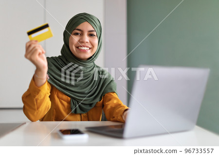 E-Commerce Concept. Smiling Muslim Lady Holding Creadit Card And Using Laptop 96733557