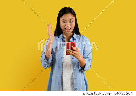 Cheerful surprised millennial korean female with down syndrome in casual with open mouth reads message on phone 96733564