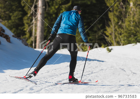 Nordic skiing or Cross-country skiing classic technique practiced by man in a beautiful panoramic trail at morning. 96733583