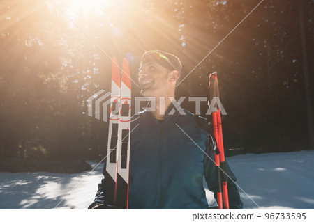 Portrait handsome male athlete with cross country skis in hands and goggles, training in snowy forest. Healthy winter lifestyle concept.  96733595