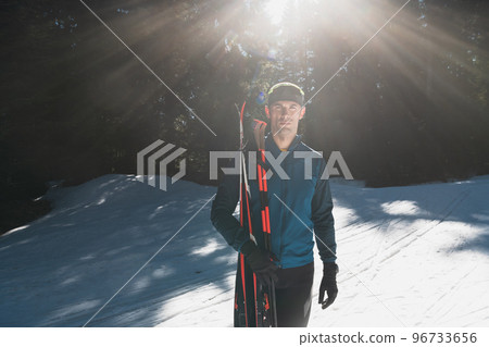 Portrait handsome male athlete with cross country skis in hands and goggles, training in snowy forest. Healthy winter lifestyle concept.  96733656
