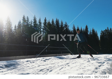Nordic skiing or Cross-country skiing classic technique practiced by man in a beautiful panoramic trail at morning. 96733667