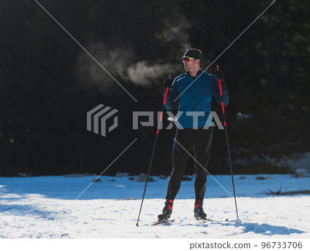 Portrait handsome male athlete with cross country skis, taking fresh breath and having break after hard workout training in a snowy forest. Healthy winter lifestyle concept 96733706