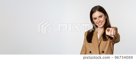Portrait of smiling enthusiastic businesswoman, saleswoman pointing finger at camera and choosing, inviting you, standing over white background 96734089