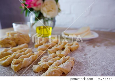 Making homemade cakes. Raw dough, butter, sugar, roses for making brushwood on a wooden tabletop. Concept on a white brick wall background. Homemade food during quarantine and lockdown. 96734352
