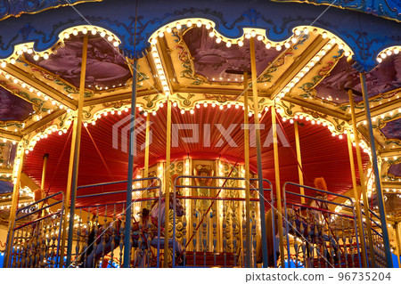 Children's Carousel roundabout, galloper close up to the roof, night illumination. Outdoor luminous. Retro Shiny details, horses, Nobody. Christmas entertainment. horizontal photo, bottom view on roof 96735204