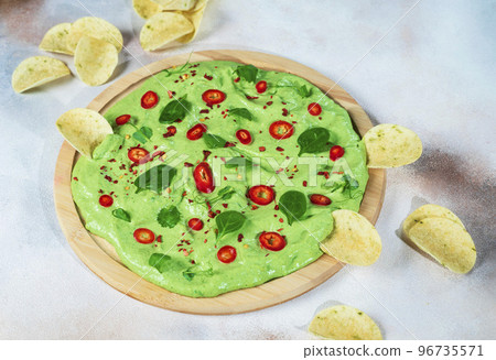 creamy avocado board with chili peppers, herbs and nachos Selective focus with blurred foreground and background creamy avocado board with chili peppers, herbs and nachos Selective focus with blurred foreground and background 96735571