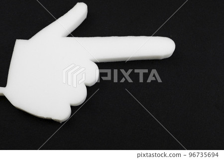 a hand made of foam rubber with an index finger on a black background. a hand made of foam rubber with an index finger on a black background. 96735694