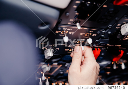 Pilot hand is controlling plane toggle switches to fly take off and landing 96736240
