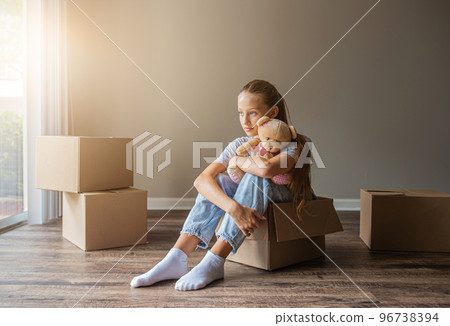 Beautiful young girl moving in new house with cardboard boxes Beautiful young girl moving in new house with cardboard boxes 96738394