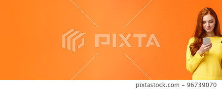 Waist-up portrait carefree modern young girl making online purchase, shopping internet using mobile application, insert credit card info smartphone, smiling, order something, orange background 96739070