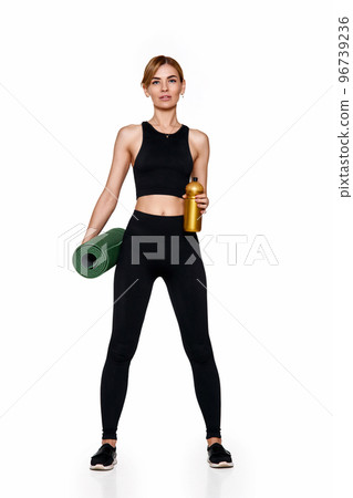 woman in sportswear holding yoga mat and bottle of water woman in sportswear holding yoga mat and bottle of water 96739236